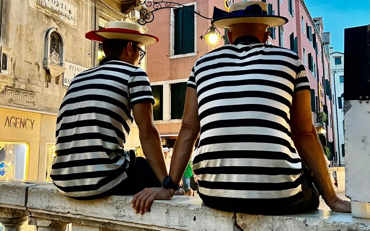 Gondoliers waiting beside a Venetian canal in autumn light